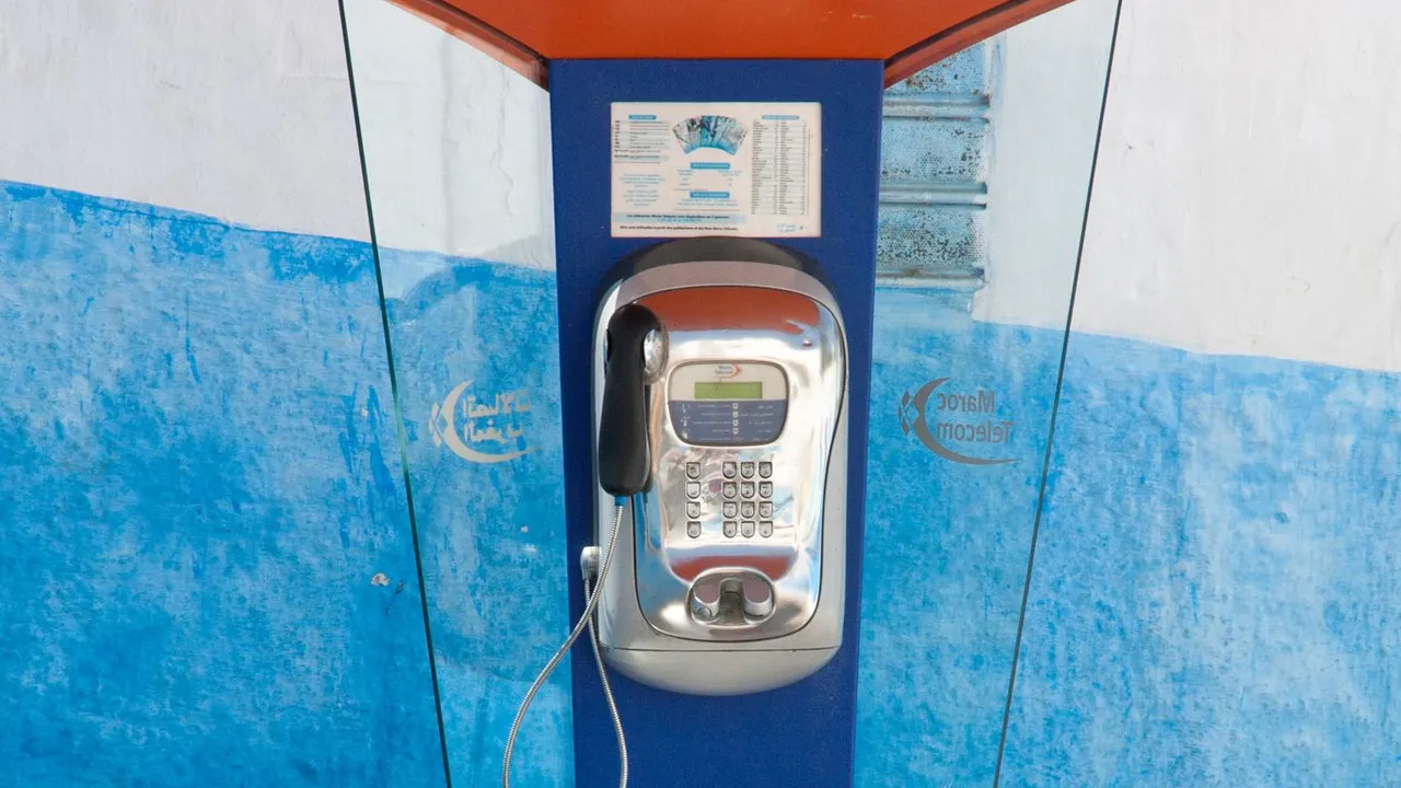 Cabine téléphonique publique bleue et orange dans une ruelle de Rabat