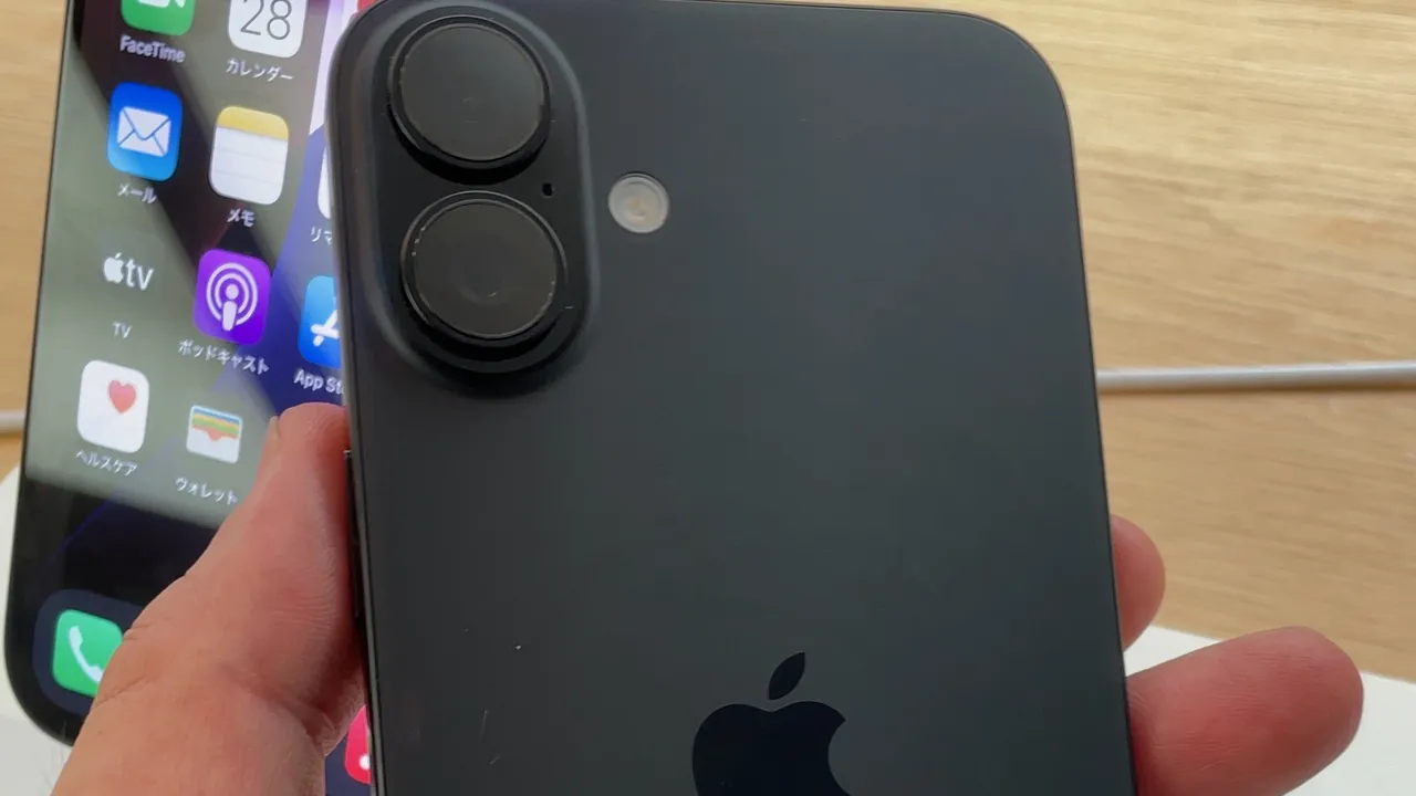 Dos d'un iPhone 16 noir tenu en main dans un magasin, avec son double appareil photo vertical
