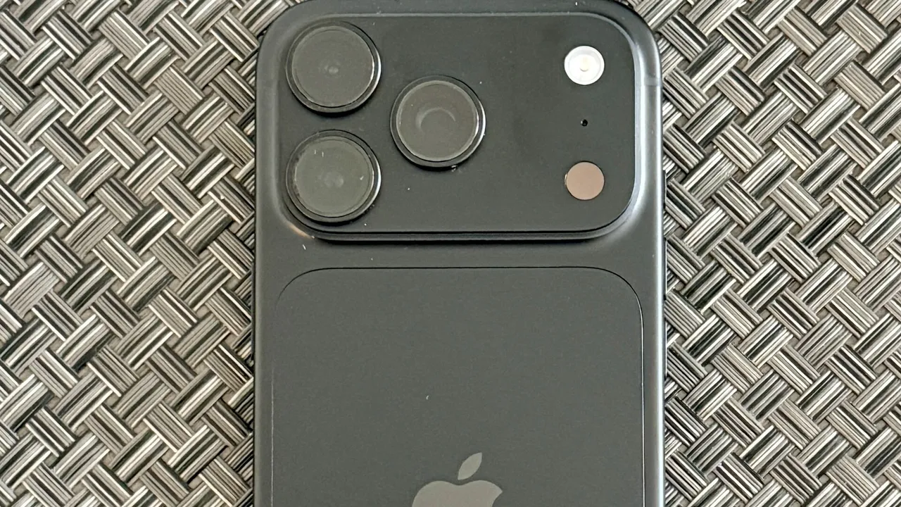 Dos d'un iPhone 18 Pro noir avec son bloc de trois caméras, posé sur une surface tressée