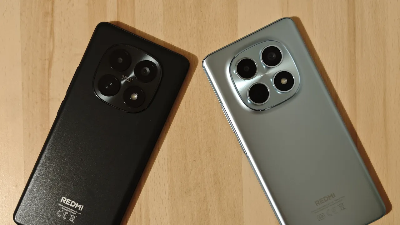 Dos de deux smartphones REDMI Note 15, l'un noir et l'autre bleu-gris, posés sur une table en bois