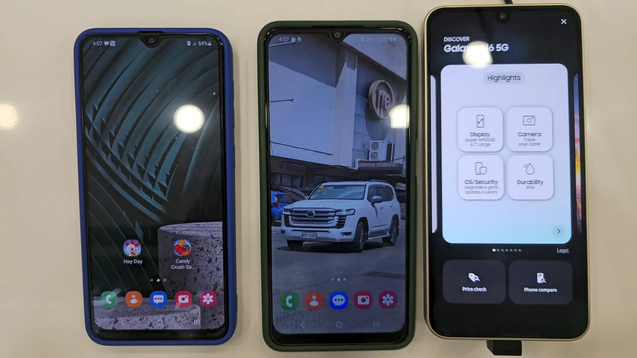 Trois smartphones Samsung Galaxy d'entrée de gamme posés côte à côte sur une table d'exposition en magasin