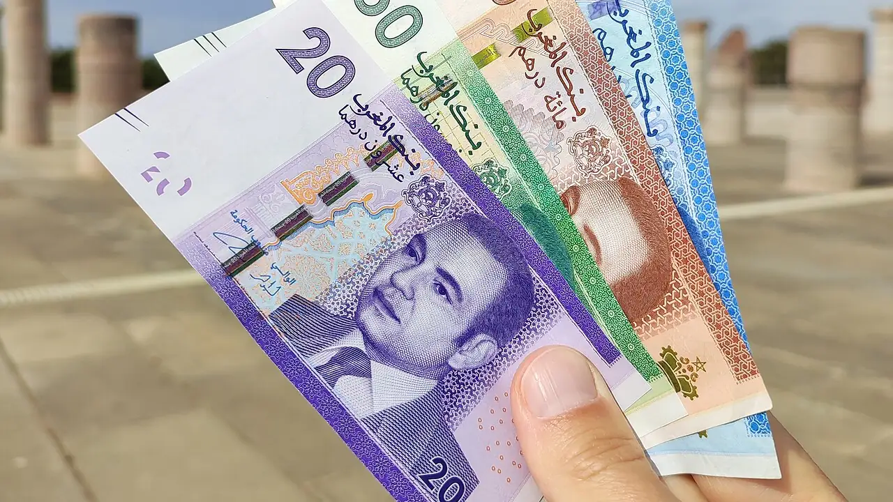 Billets de banque marocains en dirhams tenus en main sur l'esplanade de la tour Hassan à Rabat